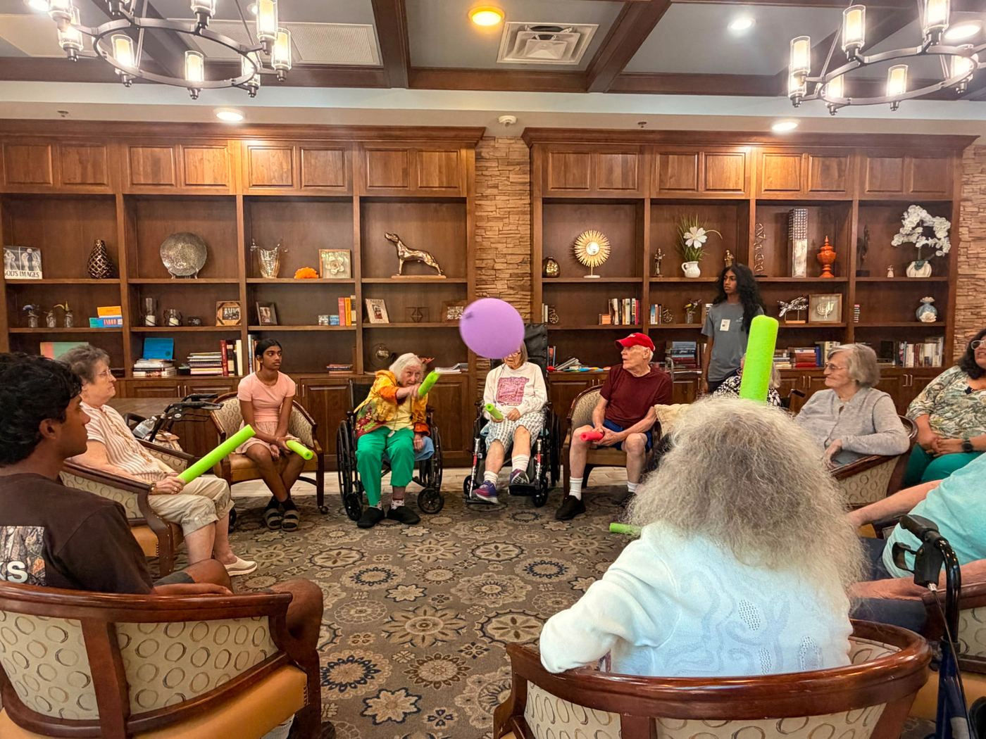 Seniors and volunteers playing a balloon game together in a partner facility lounge